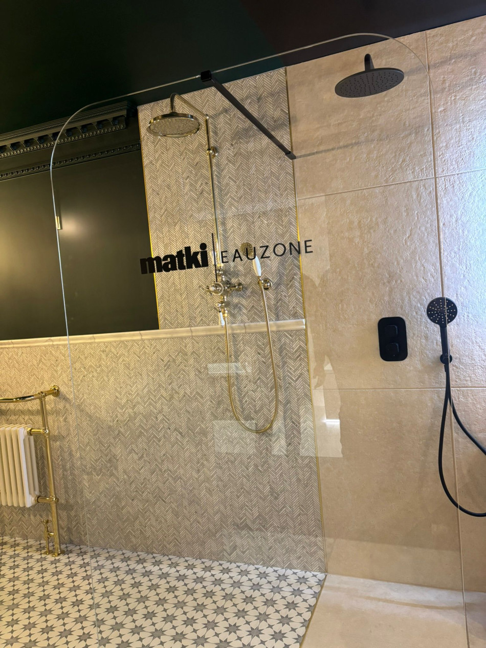 A clean bathroom featuring a shower, with neutral-coloured tiles and modern fixtures.