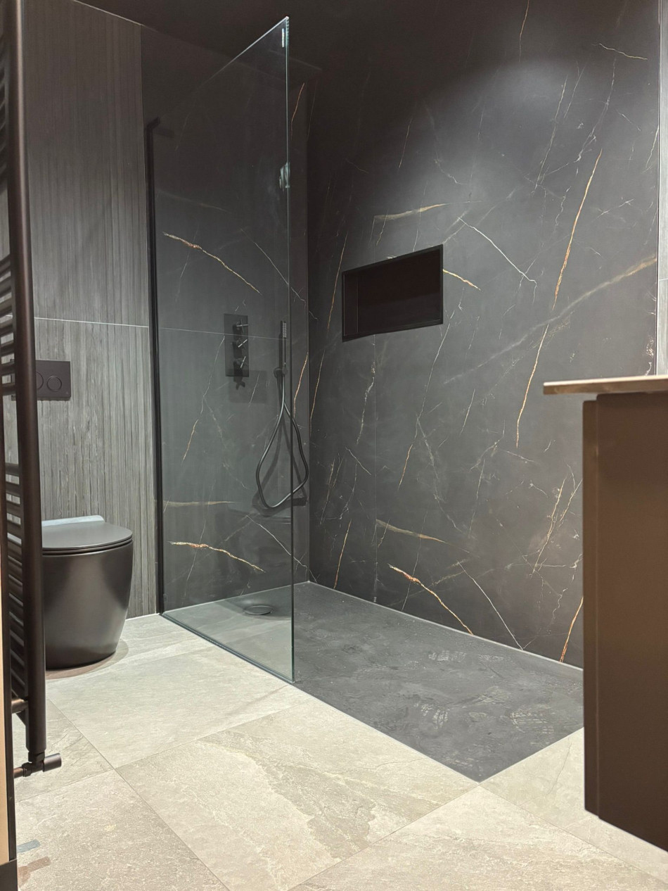 Contemporary bathroom design showcasing a spacious shower and a toilet, with minimalist decor and soft lighting.